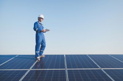 Professional inspecting solar panels on a roof